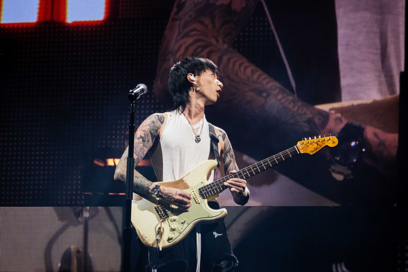Keshi playing guitar in front of the Requiem tour stage screen