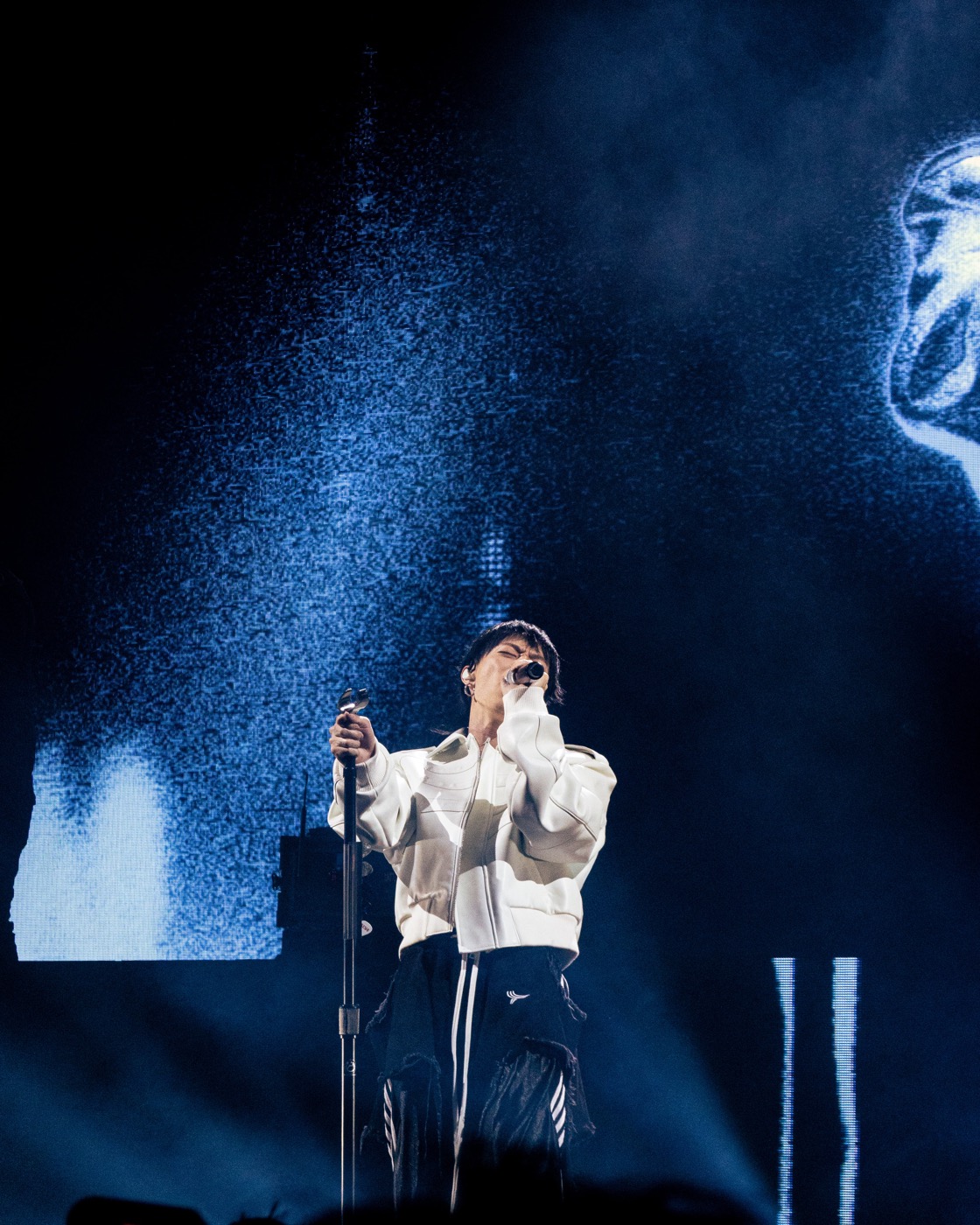 Keshi singing beneath deep blue stage visuals during the Requiem tour