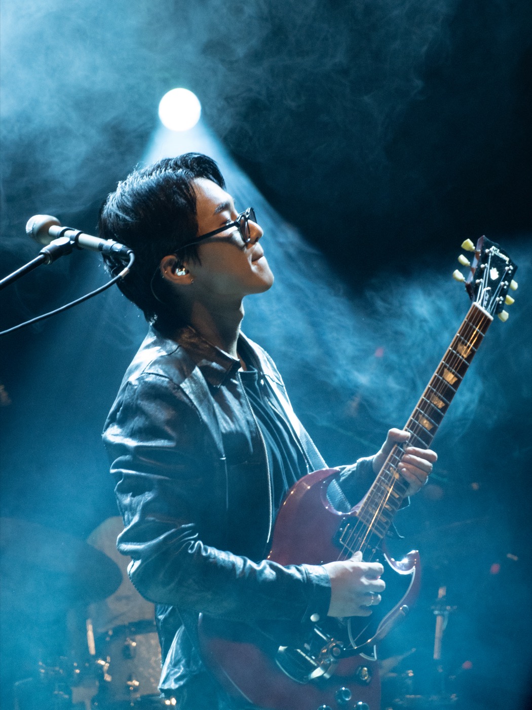 Wave to Earth guitarist performing beneath blue stage light